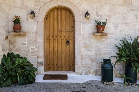 Wooden oor with two lanterns and old milk bread converted into flowerpot with a stone wallの写真素材