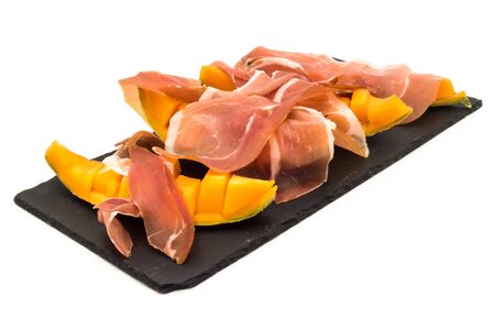 melon with ham placed on a rectangular slate plate on a white backgroundの写真素材
