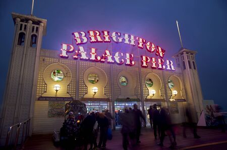 The colourful illuminated sign of Brighton Palace Pier is lit up at dusk. The famous pier at Brighton's seaside of one of the U.K.'s most popular tourist attractions.のeditorial素材
