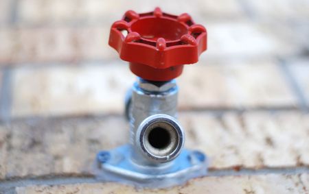 Common water spigot with a red handle on a brick wall. View from belowの写真素材