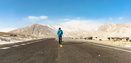 A man move on a road and see view mountain in background.の写真素材