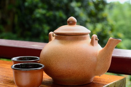 Teapot and double teacup on brown tablecloth の写真素材