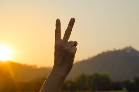 Hand showing peace victory sign against pure blue skyの写真素材