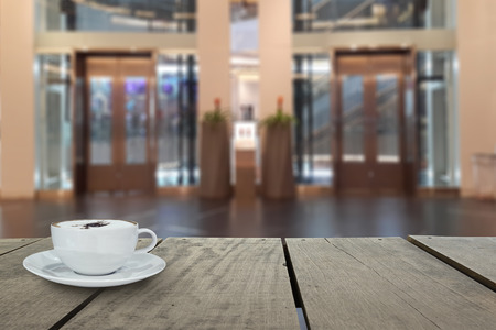 Defocus with terrace wood and cappuccino coffee with elevators in shopping mall for background usageの写真素材