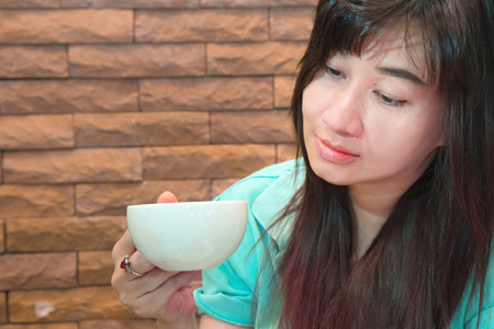 Beautiful Woman Drinking Coffee front of brick wall backgroundの写真素材