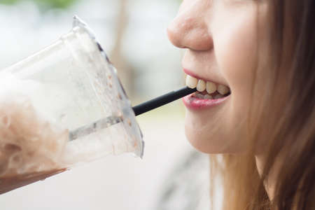 Close up Lip of asian girl and chocolate cold drink in a cup with smileの写真素材