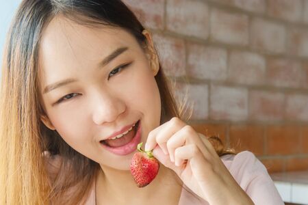 Beautiful asia woman enjoy eating strawberry fruitの写真素材