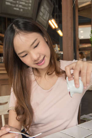 Beautiful asia woman pouring blueberry sauce topping of cheese cake.の写真素材