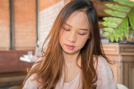 beautiful young blond woman resting in coffee shop and closing eyes for relaxationの写真素材