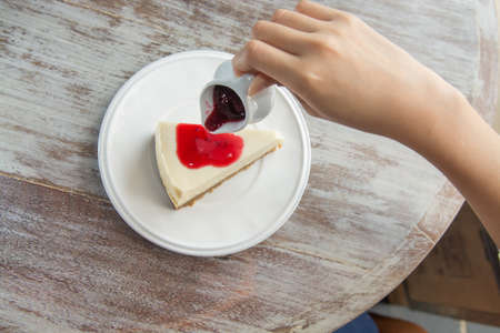 pouring blueberry sauce topping on cheese cake.の写真素材