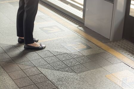 female feet standing on platform waiting train at the stationの写真素材