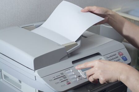 Midsection of businesswoman using fax machine in office