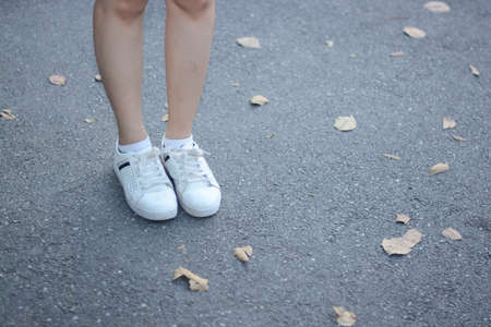 shoe and legs stand on street with barren leaf as backgroundの写真素材