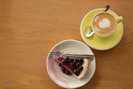Cup of cappuccino coffee and blueberry cheese pie on table in cafeの写真素材