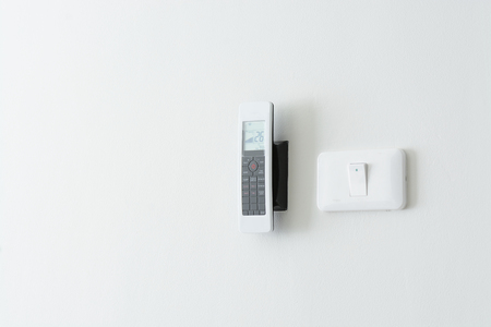Electric switch and Air conditioner remote hanging on wallの写真素材