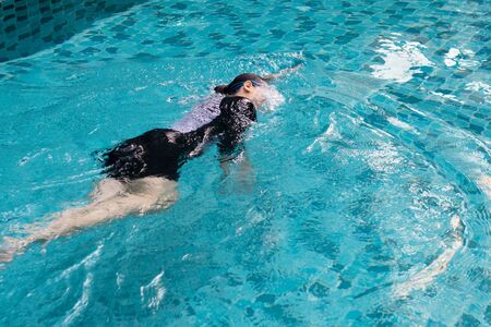 Attractive woman relaxing and swimming in pool. Asian woman enjoying summer vacations with swimming in pool.の写真素材
