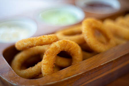 Fried cheese stick onion with sause in wooden tray.