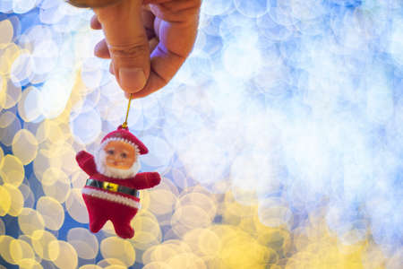 Santa claus doll hanging decorate on hands over beautiful backgroundの写真素材