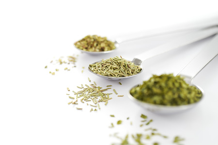 Spoon filled with dried herbs on white backgroundの写真素材