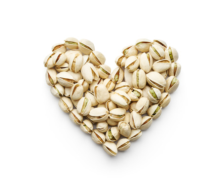 Pistachio nuts forming a heart-shape isolated on whiteの写真素材