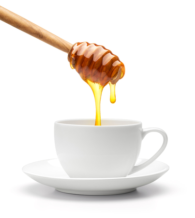 Honey dripping into cup isolated on white backgroundの写真素材