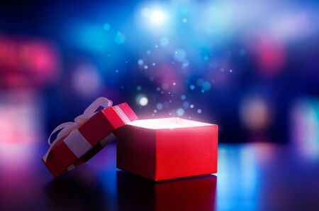 Red open gift box with magical light against blurred bokeh light