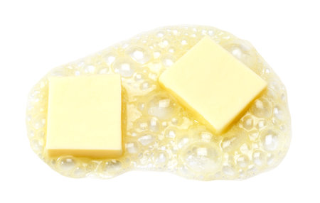 Two pieces of butter melting isolated on white backgroundの写真素材