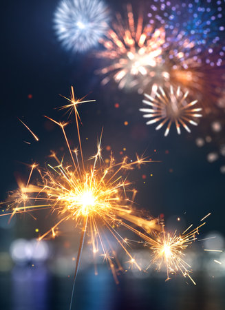 Happy New Year, Glittering burning sparkler against colorful fireworks backgroundの写真素材