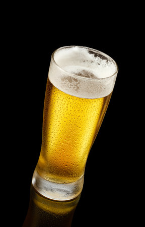 Glass of beer with a reflection over black backgroundの写真素材