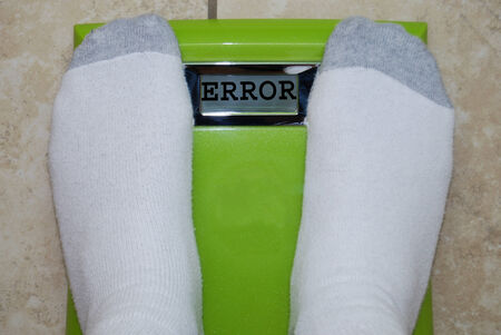 Person standing on bathroom  scale exceeding the weight limit 