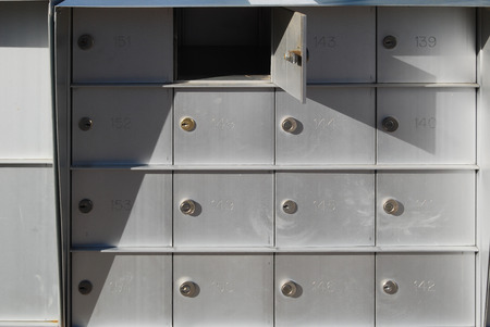 Cluster of mailboxes in a gated community with one box open.の写真素材