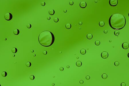 Macro shot of water droplets on glass with a green backgroundの写真素材