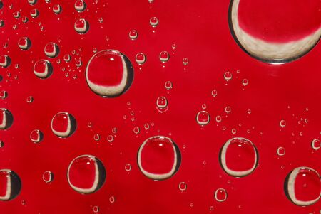 Macro shot of water droplets on glass with a red backgroundの写真素材