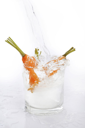 water splash in glass with baby carrotsの写真素材