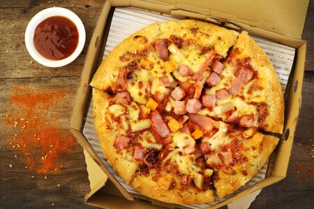 Hawaiian pizza topped with pineapple and ham , pizza from delivery boxの写真素材