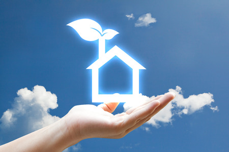 Hand and vivid eco houes icon on skyの写真素材
