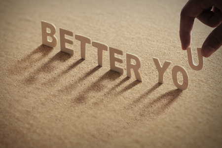 BETTER YOU wood word on compressed board with human's finger at U letterの写真素材
