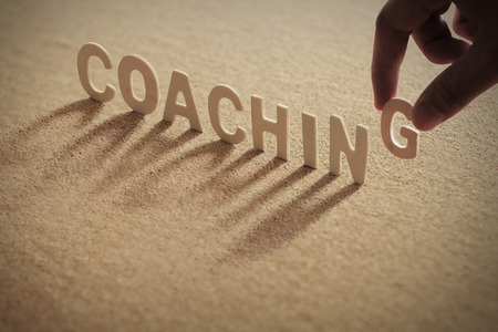 The word "coaching" wooden letters wooden on cork board background.の写真素材