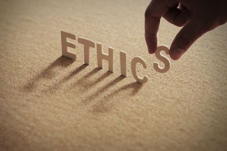 ETHICS wood word on compressed board with human's finger at S letterの写真素材