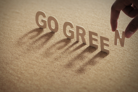 GO GREEN wood word on compressed board with human's finger at N letterの写真素材