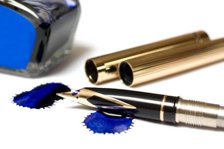 Filling of a golden pen with blue ink isolated on whiteの写真素材