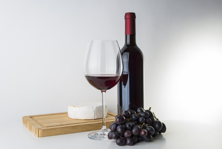 Bottle of red wine with cheese and grapesの写真素材