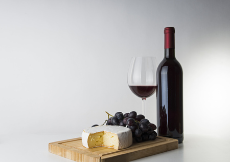 Red wine bottle with wineglass, Camembert and grapesの写真素材