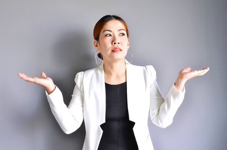 Asian business woman raising her hands on both sides on a gray background.の写真素材