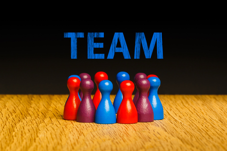 Concept for team, teamwork with text. Red blue purple pawn figures and black background on oak.
