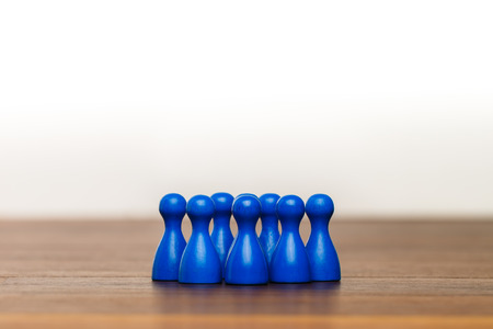 Concept for: team, group,  friends, working together. With blue pawn figures and white background on wooden surface.の写真素材