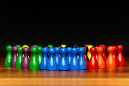 Concept for teamwork, group of people, organization. Multi color pawn figures and black background on wooden surface.の写真素材