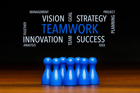 Concept for: teamwork, team, working together, goal, success. Containing text cloud with business words. With blue pawn figures and black background.の写真素材
