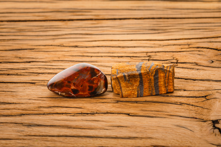 Piece of pietersite and rough tiger eye originating from Namibia Africa on wood. Pietersite metamorphic gem stone type of tiger eye.の写真素材