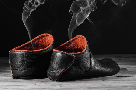 Empty slipper shoe design with smoke rise. Concept speed, smell, empty, leave. On black background with creative light.の写真素材
